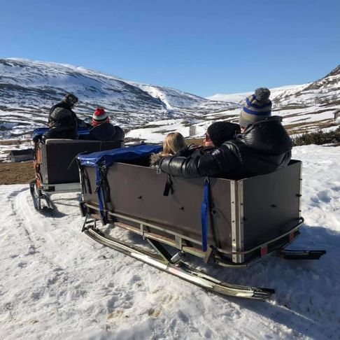 Turister ute på fjelltur sittende bak en snøscooter